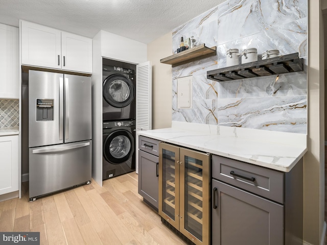 kitchen with gray cabinets, tasteful backsplash, white cabinetry, stacked washer and dryer, and stainless steel refrigerator with ice dispenser