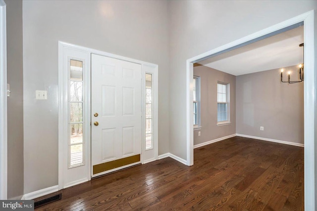 entryway featuring dark wood-type flooring and a chandelier