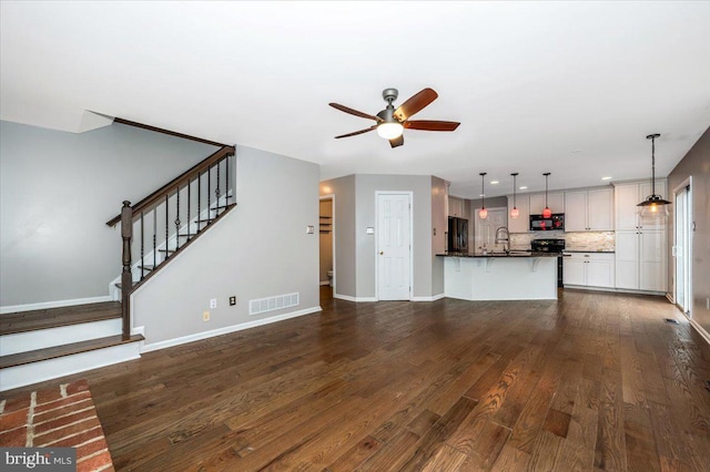 unfurnished living room with ceiling fan, dark hardwood / wood-style flooring, and sink