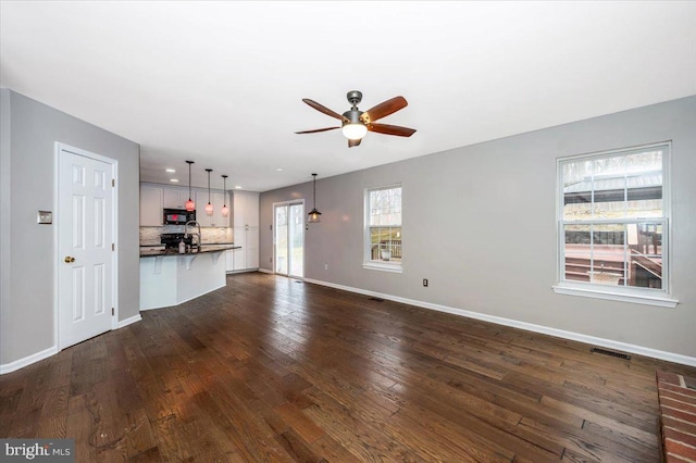 unfurnished living room featuring dark hardwood / wood-style floors, sink, and ceiling fan