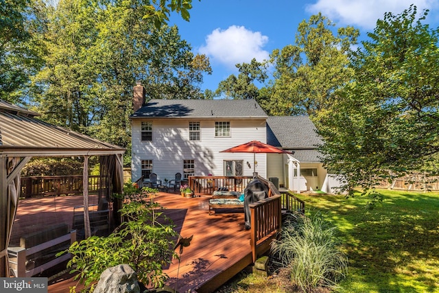 rear view of house with a deck, a gazebo, and a lawn