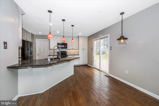 kitchen with kitchen peninsula, decorative light fixtures, sink, black appliances, and dark wood-type flooring