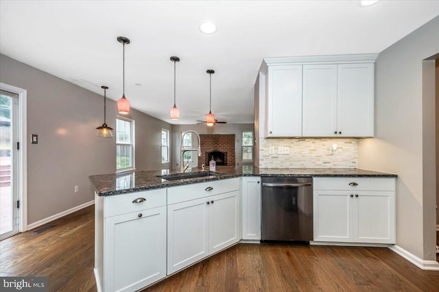 kitchen with pendant lighting, sink, white cabinets, stainless steel dishwasher, and dark stone counters