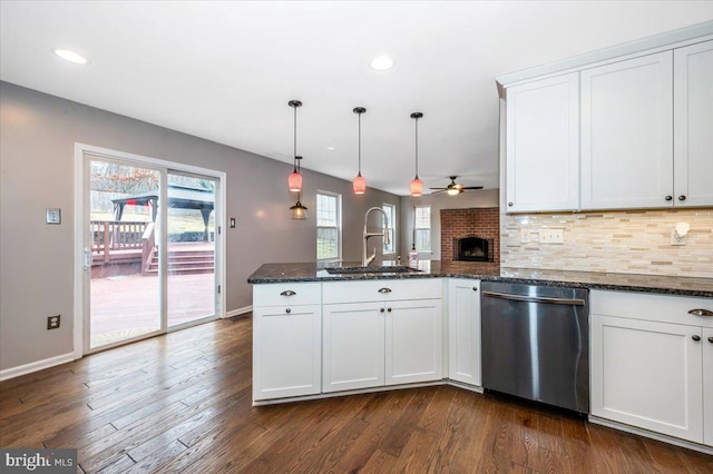 kitchen with sink, dishwasher, white cabinetry, dark stone countertops, and decorative light fixtures