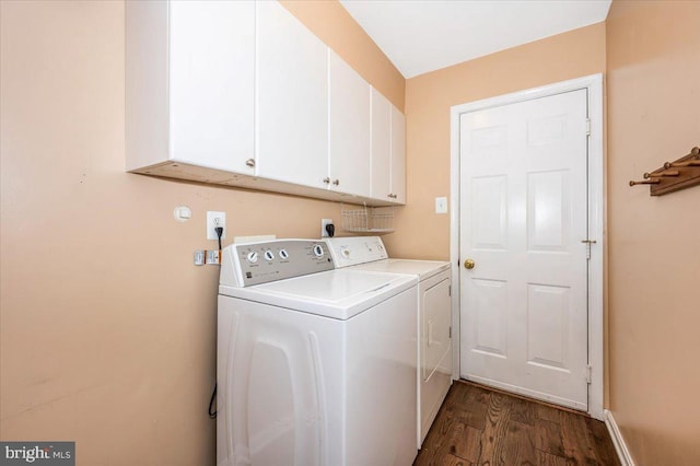 laundry area with dark wood-type flooring, cabinets, and washer and clothes dryer