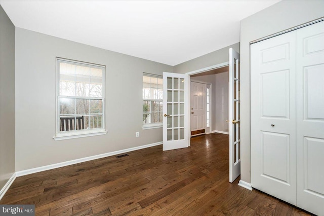 empty room with dark hardwood / wood-style flooring and french doors