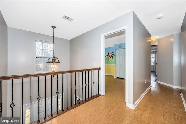 hallway with light wood-type flooring and a notable chandelier