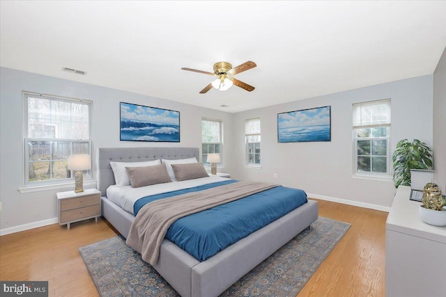 bedroom with ceiling fan, wood-type flooring, and multiple windows