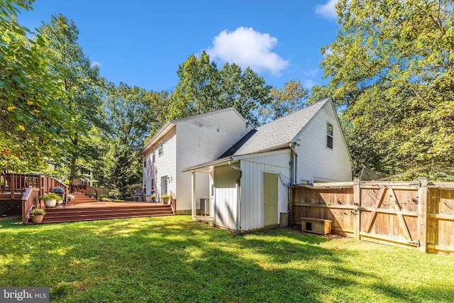 rear view of house featuring a wooden deck and a yard