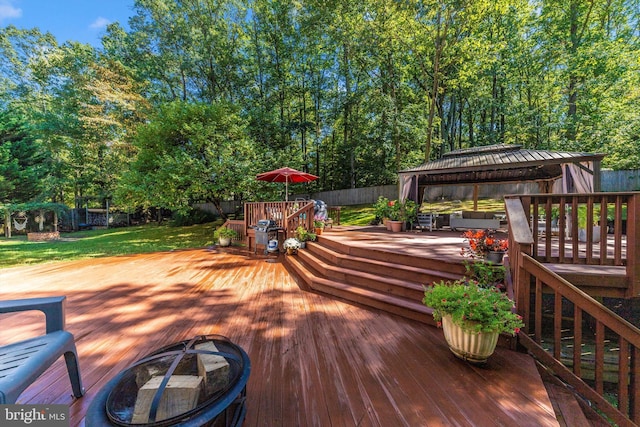 deck with a gazebo, a lawn, and a fire pit