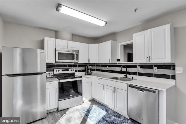 kitchen with decorative backsplash, appliances with stainless steel finishes, white cabinets, and a sink