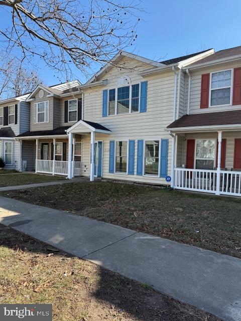 view of property featuring covered porch and a front lawn