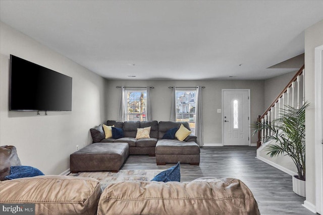 living area with stairway, baseboards, and wood finished floors