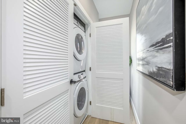 clothes washing area featuring stacked washer and dryer and light wood-type flooring