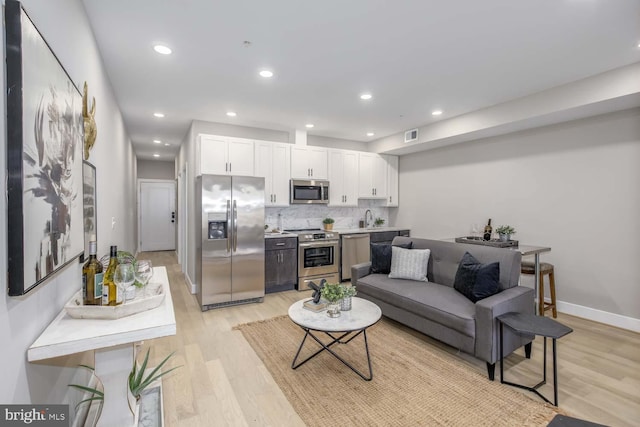 living room featuring sink and light hardwood / wood-style floors