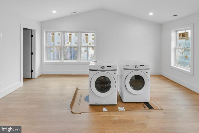 laundry room with washing machine and dryer and light wood-type flooring