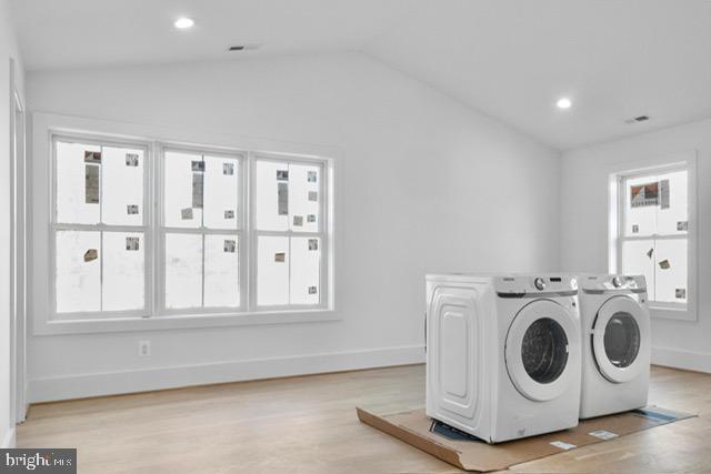 washroom with plenty of natural light, light hardwood / wood-style floors, and washing machine and clothes dryer