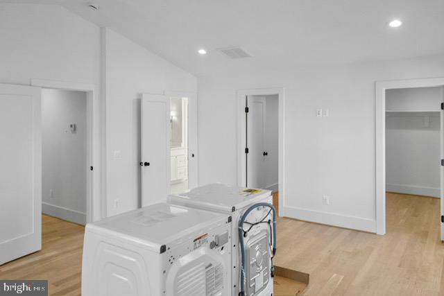 office area featuring washing machine and dryer, vaulted ceiling, and light hardwood / wood-style flooring