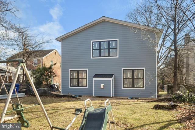 back of house featuring a playground and a lawn