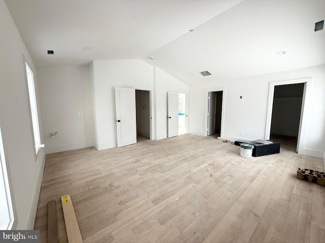 spare room featuring vaulted ceiling and light hardwood / wood-style floors