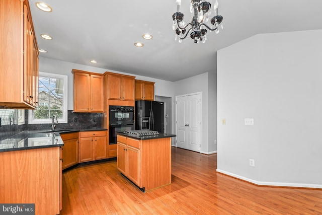 kitchen featuring sink, a center island, light hardwood / wood-style floors, black appliances, and decorative backsplash