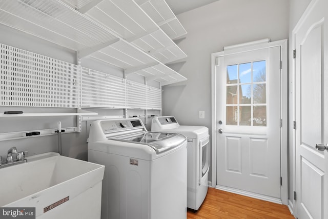 laundry area with sink, washer and dryer, and light wood-type flooring