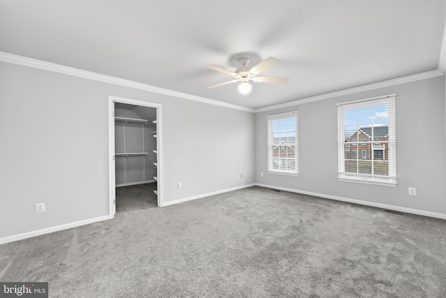 unfurnished bedroom with crown molding, ceiling fan, carpet flooring, a walk in closet, and a closet