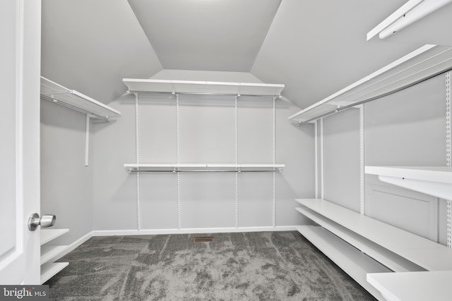 spacious closet featuring vaulted ceiling and dark carpet