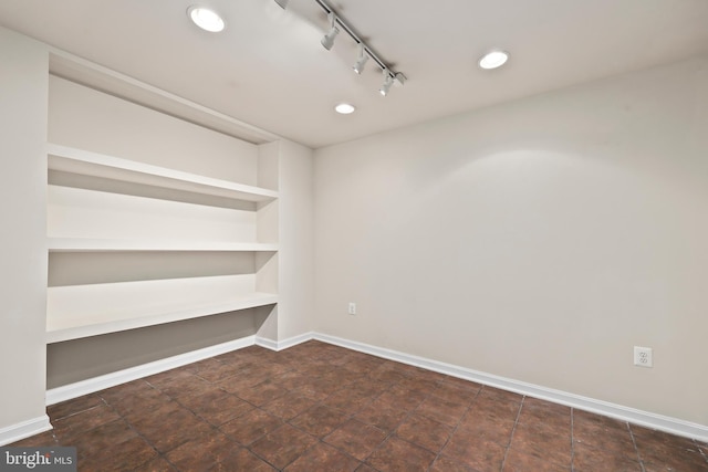 spare room featuring track lighting and built in features