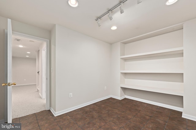 carpeted spare room with rail lighting