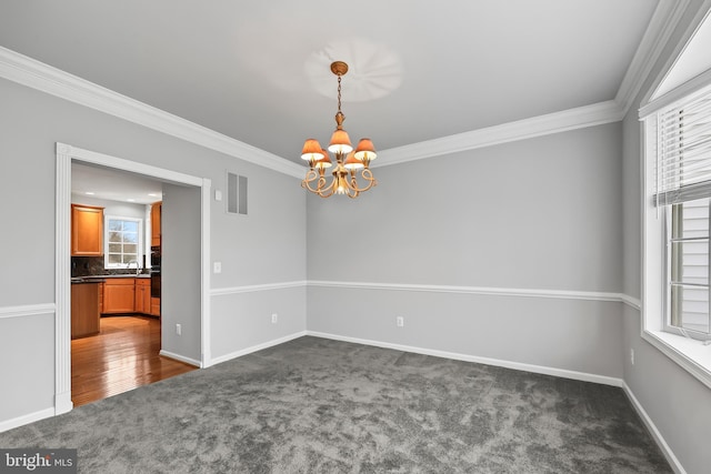 empty room featuring sink, crown molding, a chandelier, and dark colored carpet