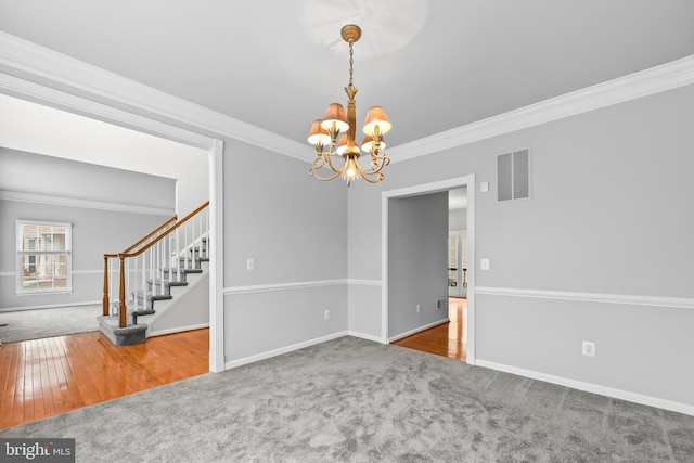 carpeted spare room featuring ornamental molding and a notable chandelier