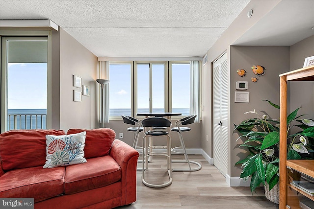 living room with a textured ceiling, a water view, and light wood-type flooring