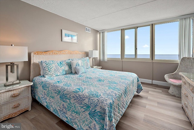 bedroom with light hardwood / wood-style floors and a textured ceiling