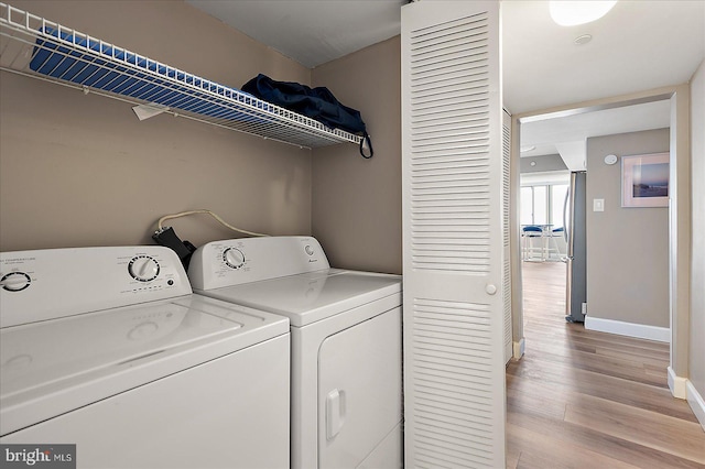 laundry room featuring washing machine and clothes dryer and light hardwood / wood-style flooring