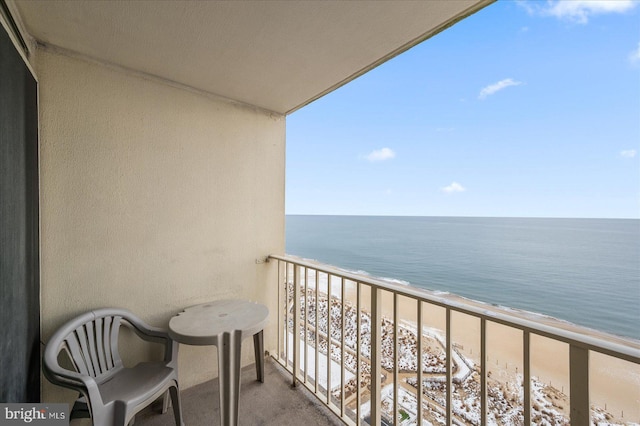 balcony with a water view and a view of the beach