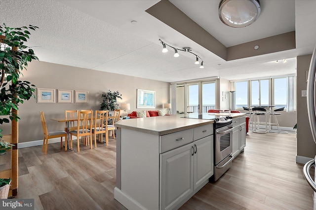 kitchen featuring plenty of natural light, light hardwood / wood-style flooring, a kitchen island, and stainless steel range with electric cooktop