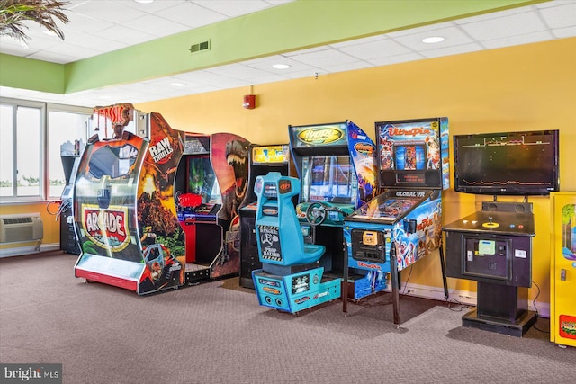 game room featuring an AC wall unit, carpet, and a drop ceiling