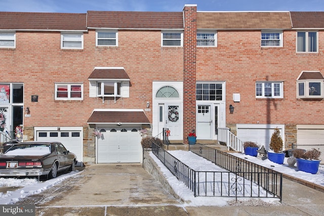 view of property featuring a garage, driveway, brick siding, and entry steps