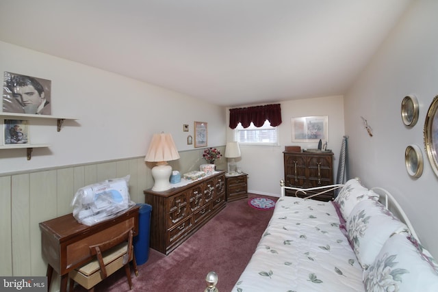 bedroom with a wainscoted wall and dark carpet