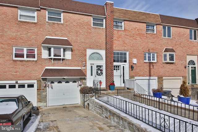 view of property featuring a garage, driveway, and brick siding