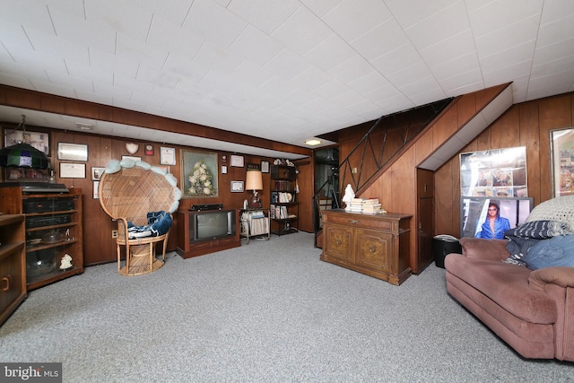 living area with light carpet, wooden walls, and stairway