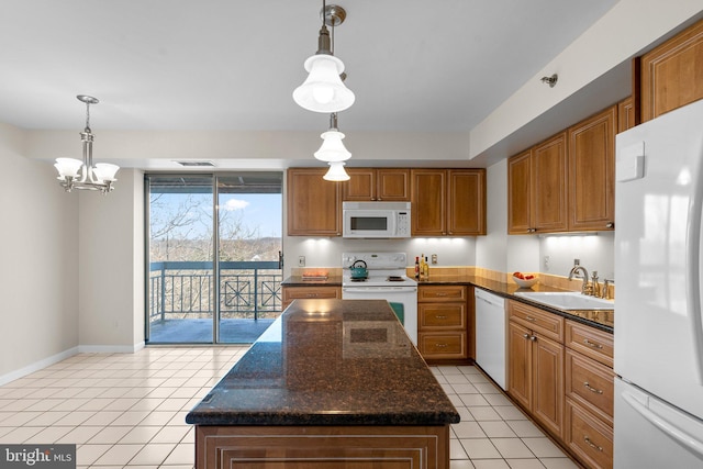 kitchen with pendant lighting, sink, white appliances, and a kitchen island