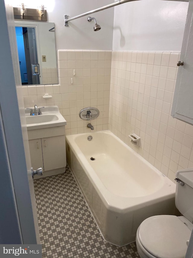 full bathroom featuring tile patterned floors, toilet, tub / shower combination, tile walls, and vanity