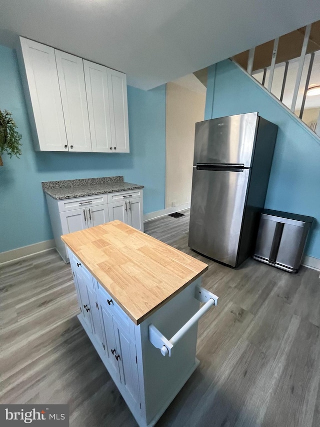 kitchen with white cabinetry, stainless steel fridge, dark hardwood / wood-style floors, and wooden counters