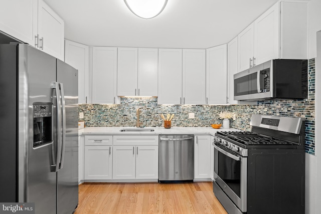 kitchen with white cabinetry, sink, backsplash, and stainless steel appliances