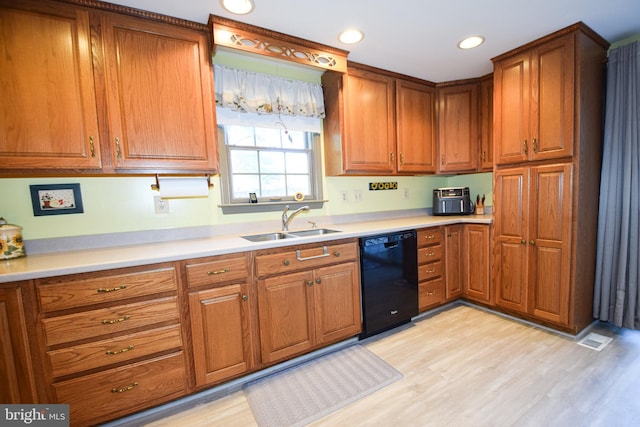 kitchen with sink, black dishwasher, and light wood-type flooring