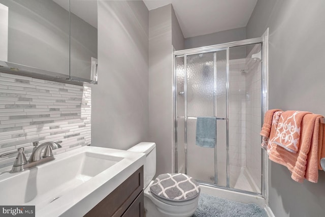 bathroom with vanity, backsplash, an enclosed shower, and toilet