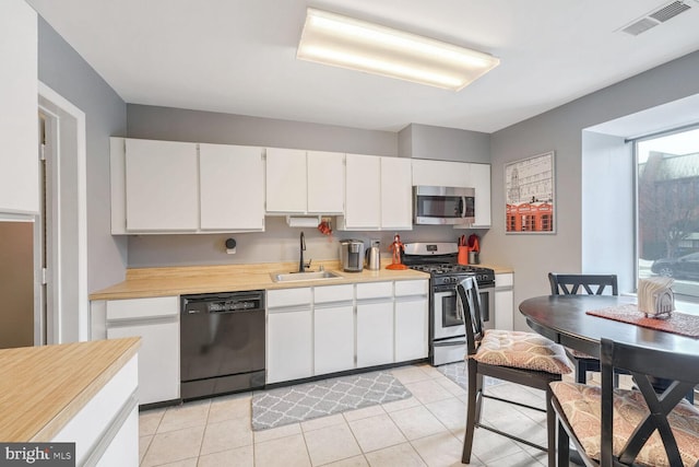 kitchen featuring light tile patterned floors, sink, white cabinets, and appliances with stainless steel finishes