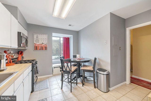 kitchen with sink, stainless steel appliances, white cabinetry, and light tile patterned floors